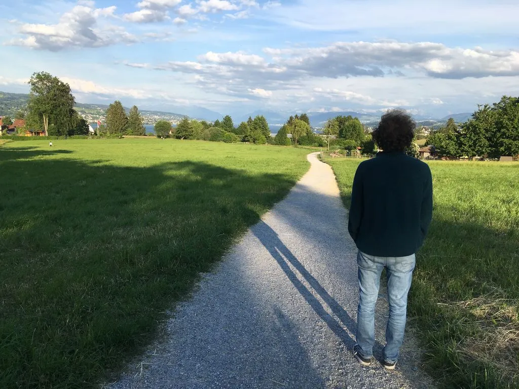 Person auf Feldweg blickt in die Ferne.