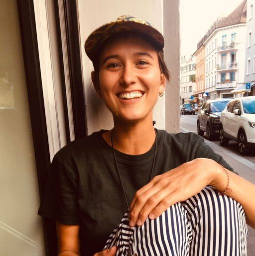 Junge lächelnde Frau sitzt an einem Fenster