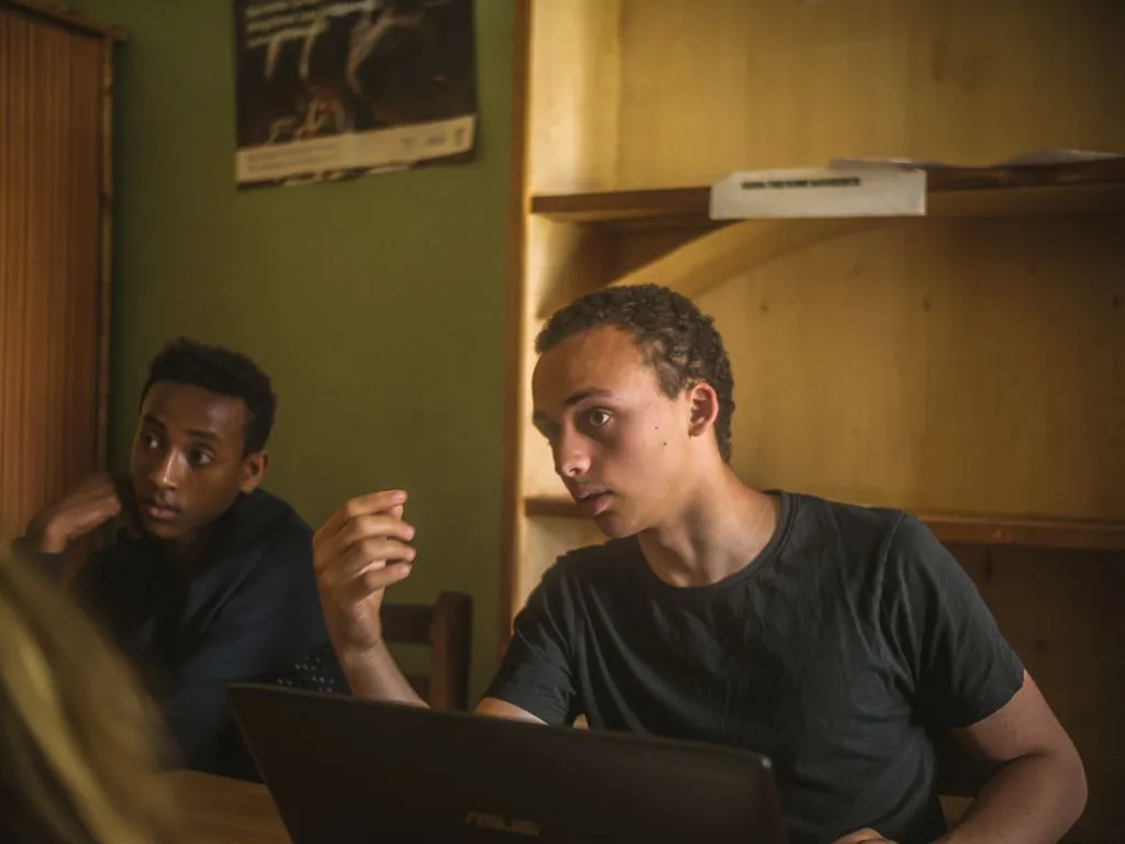 Junger Mann diskutiert an einem Tisch