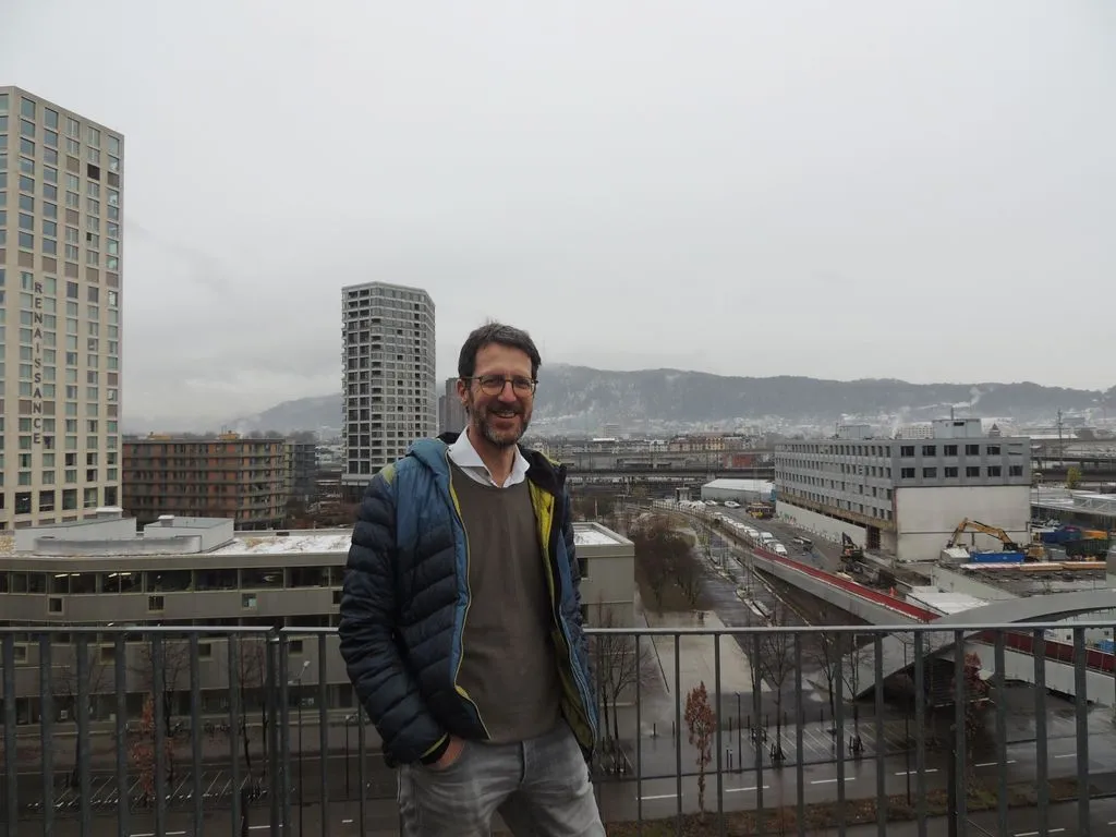 Person steht auf Terrasse vor einer Baustelle in einer Stadt.