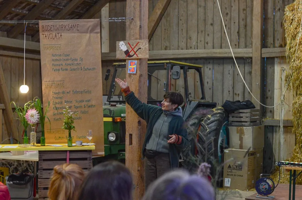Junge Frau macht Vortrag vor Publikum in einer Scheune.