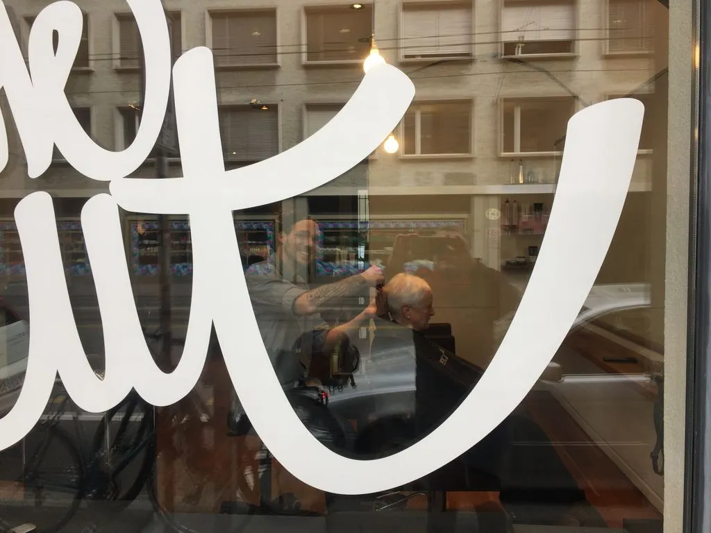 Coiffeur schneidet Haare eines Kunden.