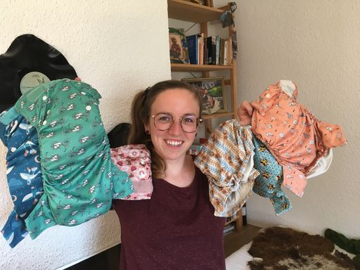 Junge Person zeigt bunte Stoffwindeln.