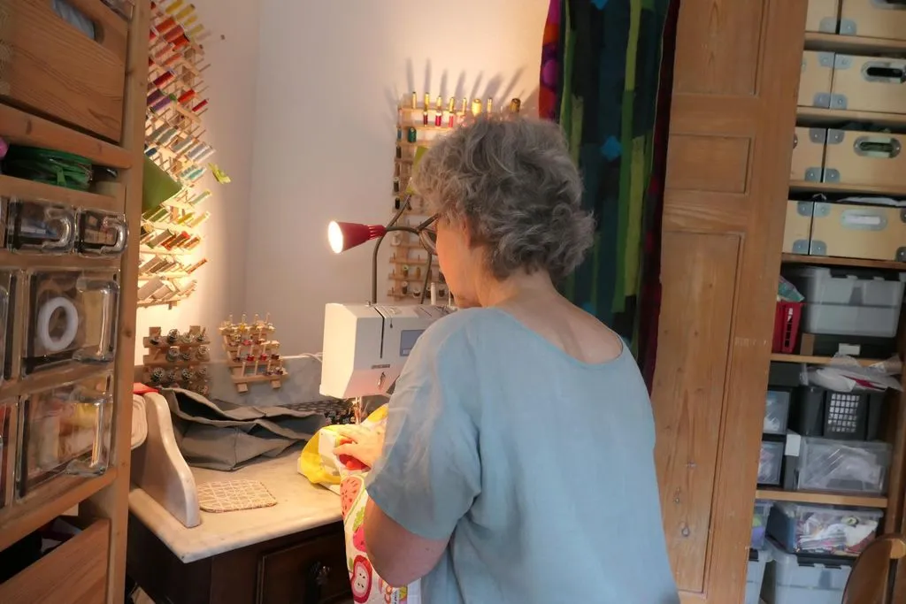 Frau sitzt an Nähmaschine.