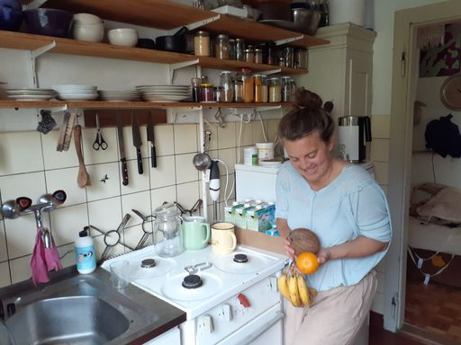 Junge Person jongliert mit Früchten in der Küche.