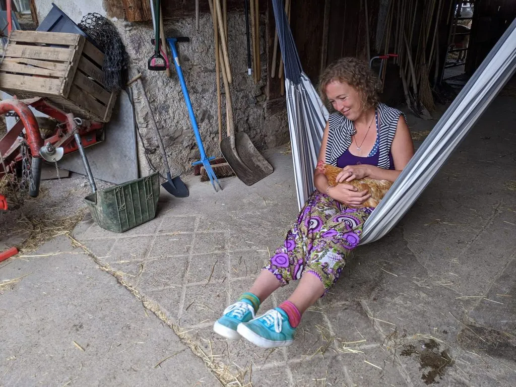 Frau in Hängematte mit Huhn im Schoss