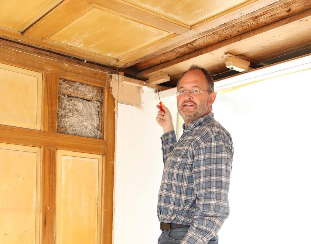 Mann renoviert alte Holzdecke.