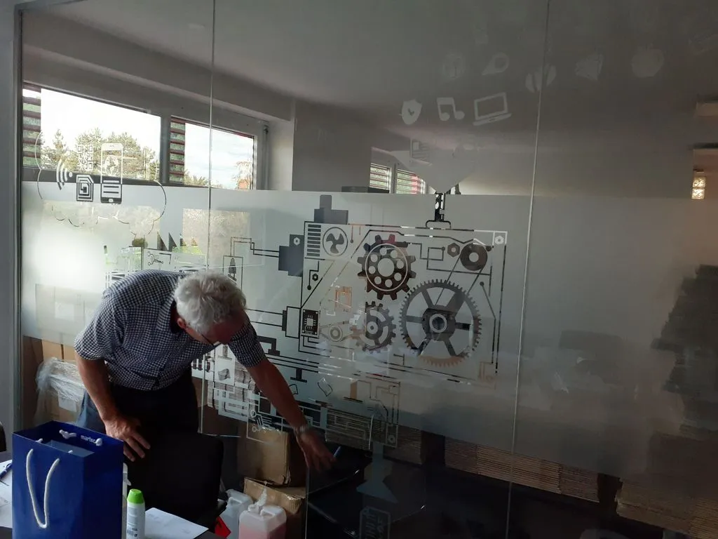 Ein Mann steht vor technischen Entwürfen an einer Wand.