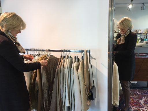 Eine ältere Frau geht Kleider an einem Kleiderständer durch