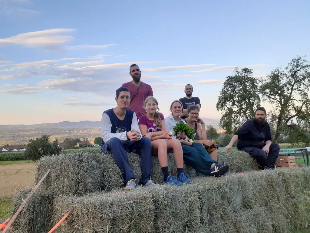 Erwachsene und Kinder sitzen auf einem Stapel Heuballen auf Feld