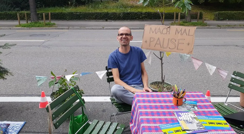 Mann sitzt auf Stuhl auf Parkplatz.