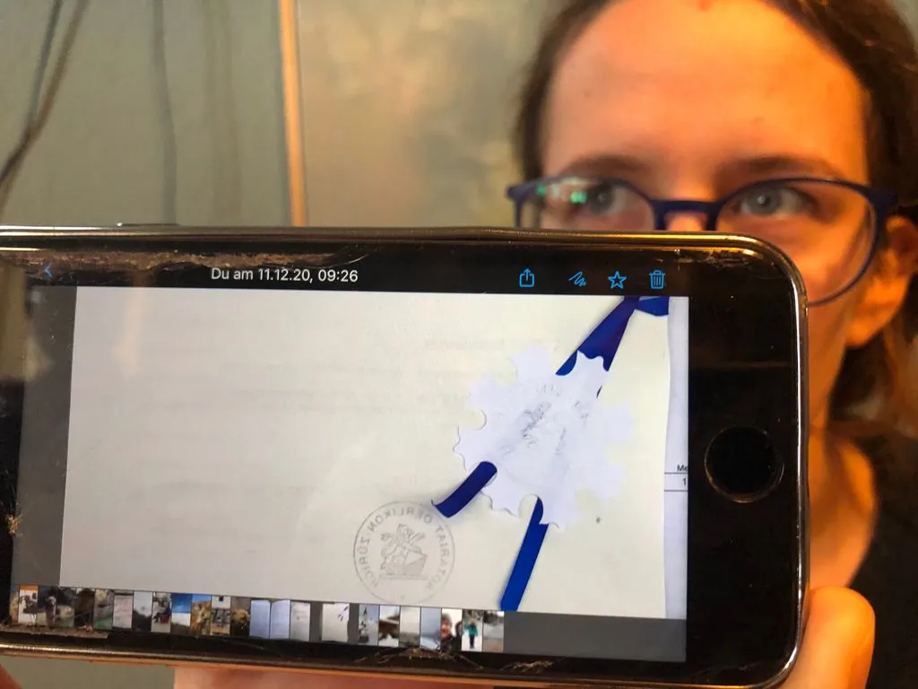 Frau zeigt einen amtlichen Stempel auf ihrem Smartphone.