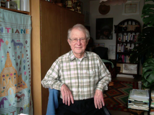 Älterer Mann mit kariertem Hemd im Wohnzimmer.