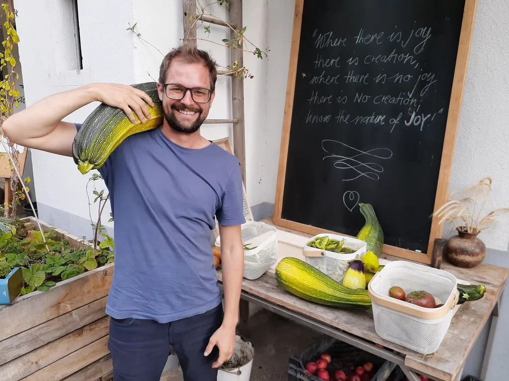 Lachende Person mit grosser Zucchetti auf Schulter.